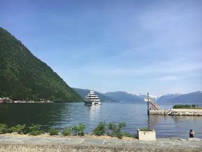 a cruise ship in a lake with mountains in the background at Blix Hotel in Vikøyri