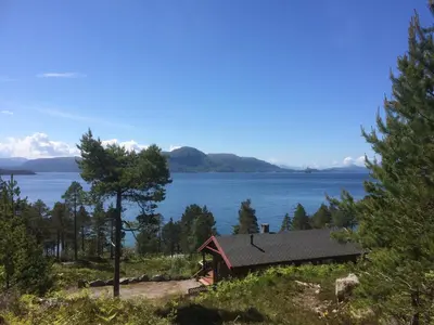 a house on a hill next to a body of water at Tustna Ladestasjon in Hals