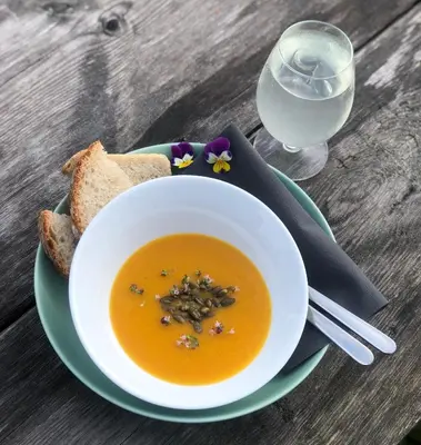 a bowl of soup on a plate with bread and a glass of water at Tustna Ladestasjon in Hals