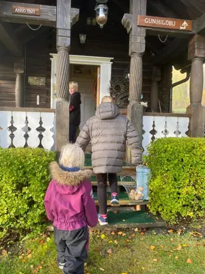 a woman and a child walking out of a house at Hesla Farm in Gol