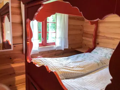 a bed in a log cabin with a window at Tjonnas Farm Stay in Sauland