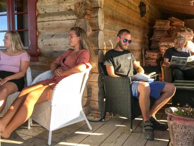 a group of people sitting in chairs on a porch at Tjonnas Farm Stay in Sauland