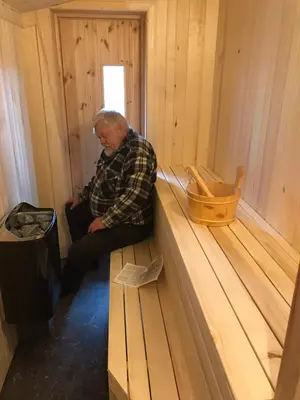 a man sitting on a bench in a cabin at Tjonnas Farm Stay in Sauland