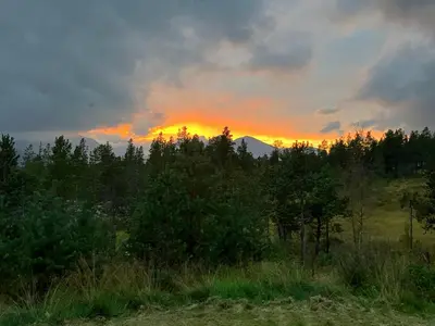 a sunset in a field with trees and clouds at Rondane Sollia Friluftsliv Øvre Nordli in Sollia