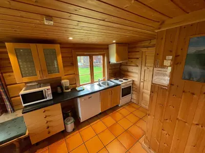 a kitchen in a log cabin with a stove and microwave at Rondane Sollia Friluftsliv Øvre Nordli in Sollia