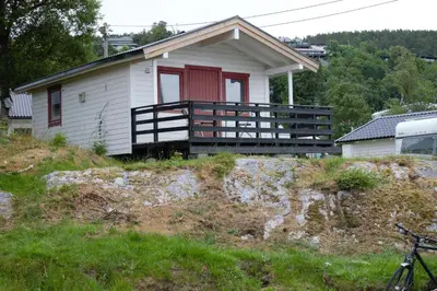 a small white house with a red door at Volsdalen Camping in Ålesund