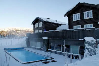 a house with a swimming pool in the snow at Ilsetra Hotell in Hafjell
