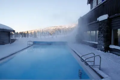 a swimming pool covered in snow next to a building at Ilsetra Hotell in Hafjell