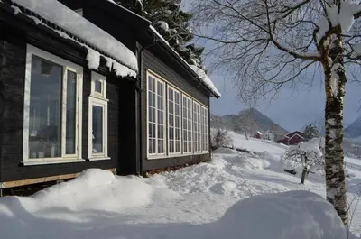 a house with snow on the ground next to a window at Klara House in Isfjorden