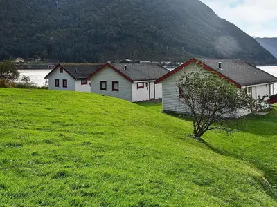 a group of houses on a grassy hill with a mountain at 5 person holiday home in Selje-By Traum in Selje