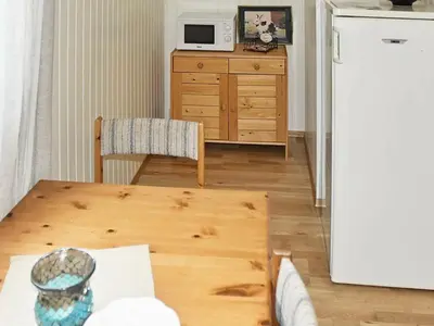 a living room with a table and a white refrigerator at 6 person holiday home in Leirvik i Sogn-By Traum in Bø