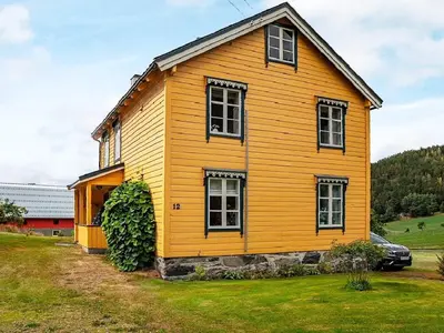 a yellow house in a field with a car in front at 8 person holiday home in Liabygda-By Traum in Eidsdal