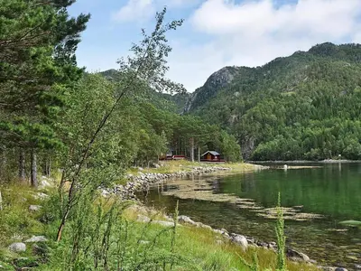 a body of water with a cabin in the background at 8 person holiday home in Sundlandet in Snildal