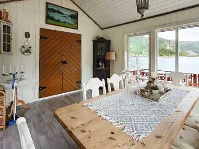 a dining room with a wooden table and white chairs at 8 person holiday home in Sundlandet in Snildal