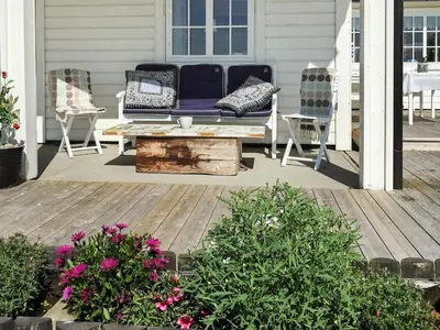a porch with a bench and two chairs and flowers at 10 person holiday home in Tornes I Romsdal in Tornes