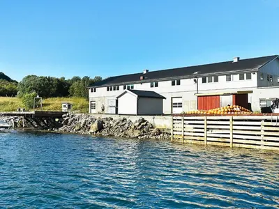 a building next to a body of water with a bunch of fruit at 8 person holiday home in Oksvoll in Oksvoll