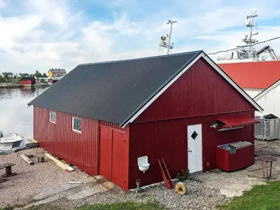 a red barn with a black roof next to the water at 8 person holiday home in averøy in Henda