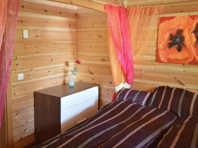 a bedroom with a bed and a dresser in a log cabin at 10 person holiday home in EIDSVÅG in Rød