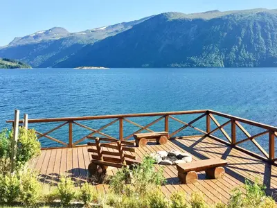 two benches sitting on a wooden deck near a body of water at 10 person holiday home in EIDSVÅG in Rød