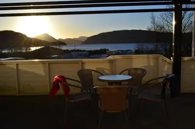a table and chairs on a balcony with a view of a lake at VIKEDAL VERTSHUS hotel in Vikedal