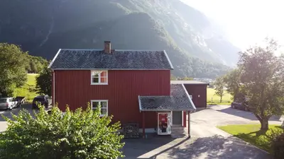a red house with a mountain in the background at Åndalsnes Hostel in Åndalsnes