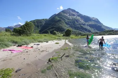 a couple of people walking on the beach with surfboards at Åndalsnes Hostel in Åndalsnes