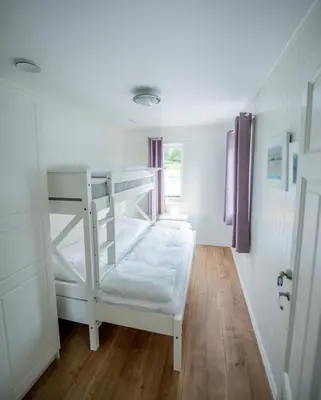 a white bunk bed in a room with wooden floors at Viken Holiday Home in Viksdalen
