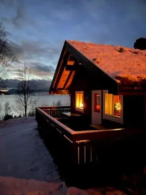 a log cabin with lights in the windows of it at Kjøsnes Feriehytter in Skei