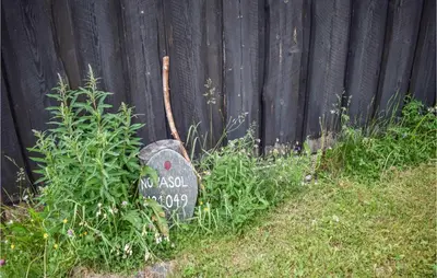 a sign in the grass next to a fence at Three-Bedroom Holiday Home In Heidal in Heidal