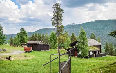 a house in a field with mountains in the background at Three-Bedroom Holiday Home In Heidal in Heidal