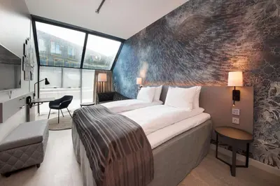 a hotel room with a large bed and a chair at Scandic Flesland Airport in Bergen