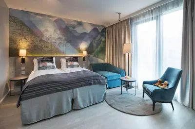 a bedroom with a large bed and a blue chair at Scandic Flesland Airport in Bergen