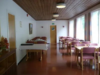 a room with chairs and tables and a white piano at HI Borlaug Vandrerhjem in Borgund