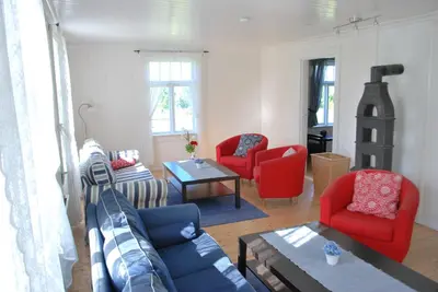 a living room with red chairs and a blue couch at Idylliske Evjua ved Mjøsa in Skreia