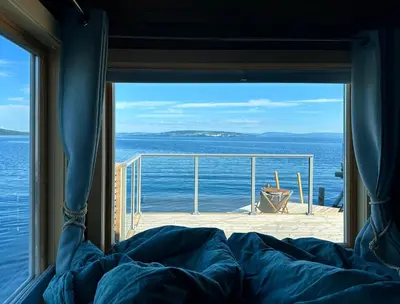 a bedroom window with a view of the ocean at Idylliske Evjua ved Mjøsa in Skreia
