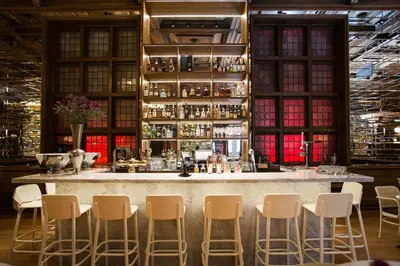 a bar with white stools in a room with windows at Bergen Børs Hotel in Bergen