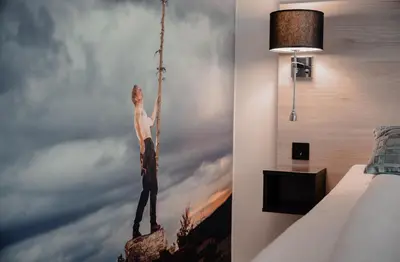 a painting of a man on a rope swing in a bedroom at Thon Hotel Vinstra in Vinstra