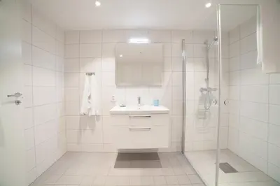 a white bathroom with a sink and a shower at BJØRVIKA APARTMENTS, Damsgård Area, Bergen city center in Bergen