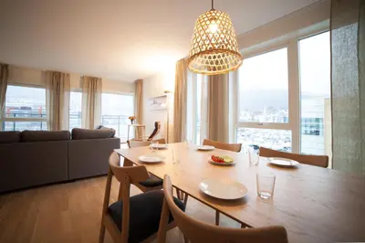 a dining room table with chairs and a large window at BJØRVIKA APARTMENTS, Damsgård Area, Bergen city center in Bergen