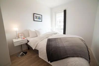 a bedroom with a bed with a nightstand and a window at BJØRVIKA APARTMENTS, Damsgård Area, Bergen city center in Bergen