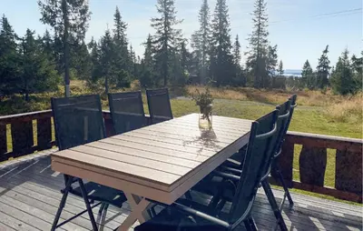 a wooden table and chairs on a deck at Cozy Home In Sjusjøen in Sjusjøen