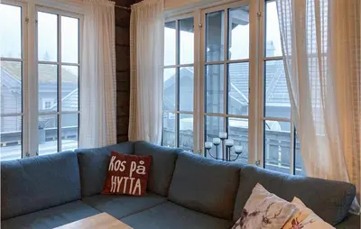 a blue couch in a room with large windows at 3 Bedroom Nice Home In Sjusjøen in Sjusjøen