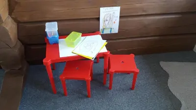 a table and two red chairs and a table with a drawing at Sæteråsen Hytter & Camping Trysil in Trysil