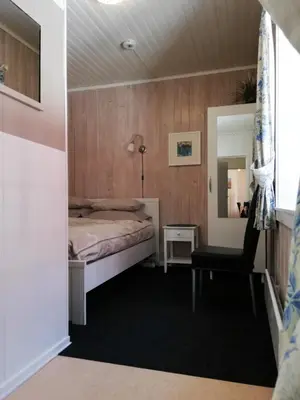a small bedroom with a bed and a chair at Løvheim Gjestehus - Anneks in Sauland