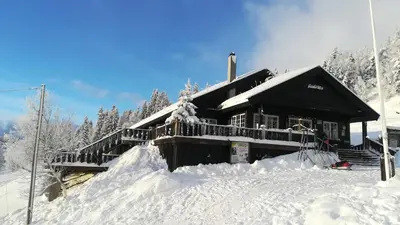 a house covered in snow with a pile of snow at Gamlestølen Fjellstue in Etnedal