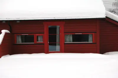 a red barn with snow on the roof at Jorekstad Ferieleiligheter in Fåberg