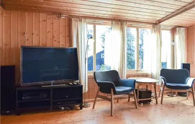 a living room with a television and two chairs and a table at Gorgeous Home In Sjusjøen With Sauna in Sjusjøen