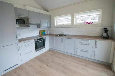 a kitchen with white cabinets and a wooden floor at Lofthus Camping in Lofthus