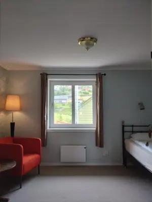 a bedroom with a window and a bed and a chair at Hardanger Rom & Harmonium 