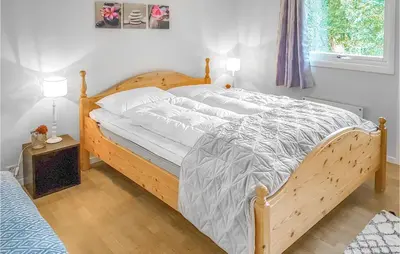 a bedroom with a large bed with a wooden frame at Three-Bedroom Holiday Home In Vikanes in Eiknes